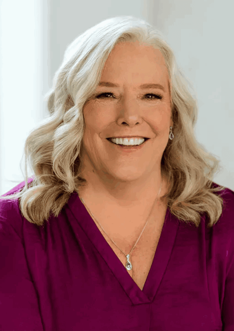 Smiling woman with long, wavy gray hair.