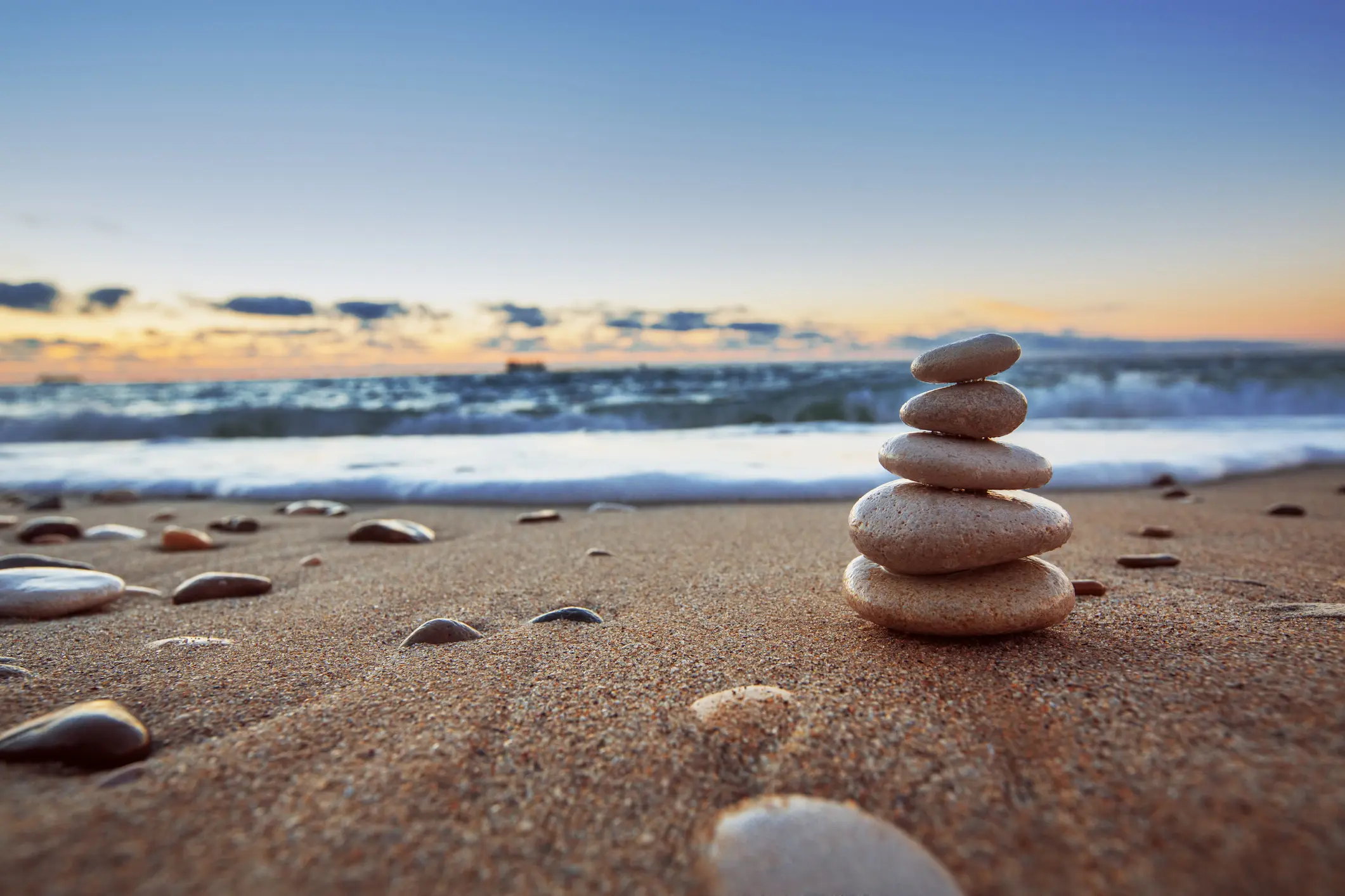 Stacked stones on beach at sunset